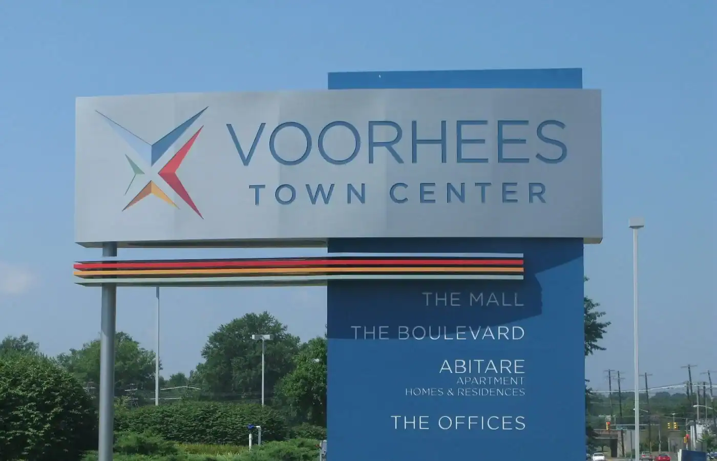 A blue and silver sign for Voorhees Town Center, seen by many Camden County painters, listing The Mall, The Boulevard, Abitare Apartment Homes & Residences, and The Offices.